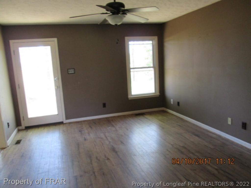 5504 Percy Strickland Road Godwin, NC 28344 - Photo 5 of 15 an empty room with wooden floor fan and windows