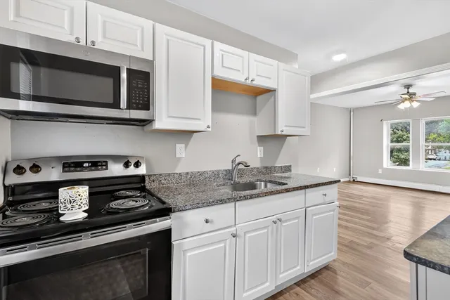 a kitchen with stainless steel appliances granite countertop a sink dishwasher a stove microwave and oven with white cabinets