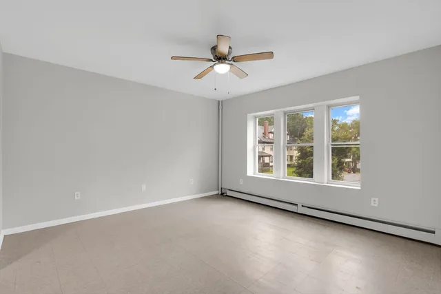 an empty room with a window and a ceiling fan