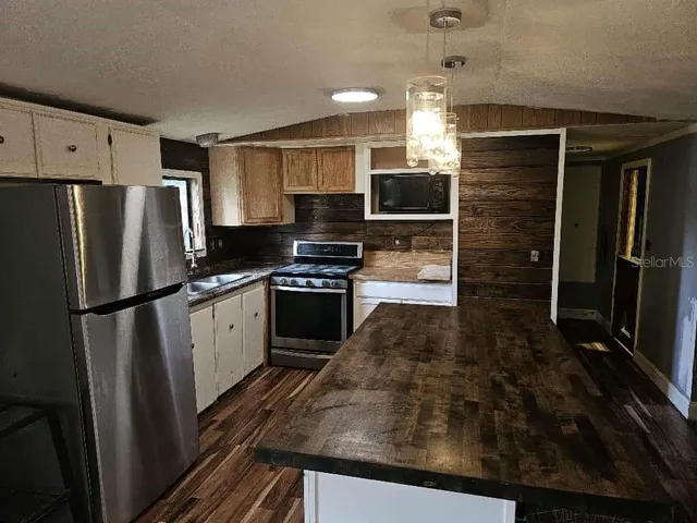 a kitchen with granite countertop a refrigerator and a stove top oven