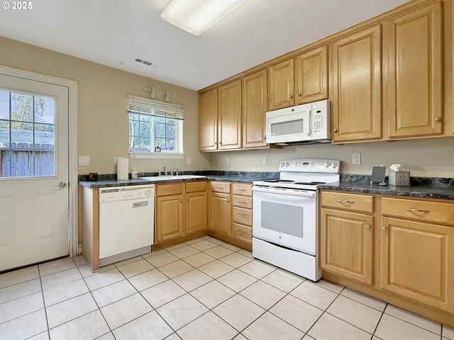 a white kitchen with granite countertop cabinets and white appliances