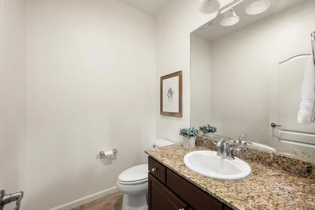 a bathroom with a granite countertop sink a mirror and a toilet