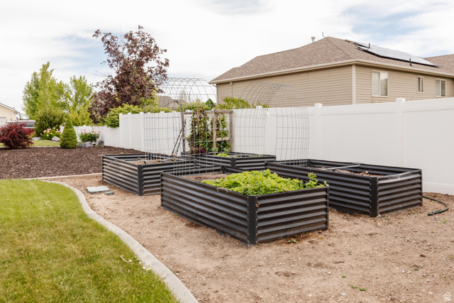 972 West 2840th Street South Logan, UT 84321 - Photo 42 of 46 Landscaped garden area featuring four corrugated metal raised garden beds, a white vinyl privacy fence, and an irrigation system