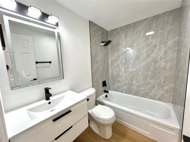 a bathroom with a bathtub shower sink vanity and toilet
