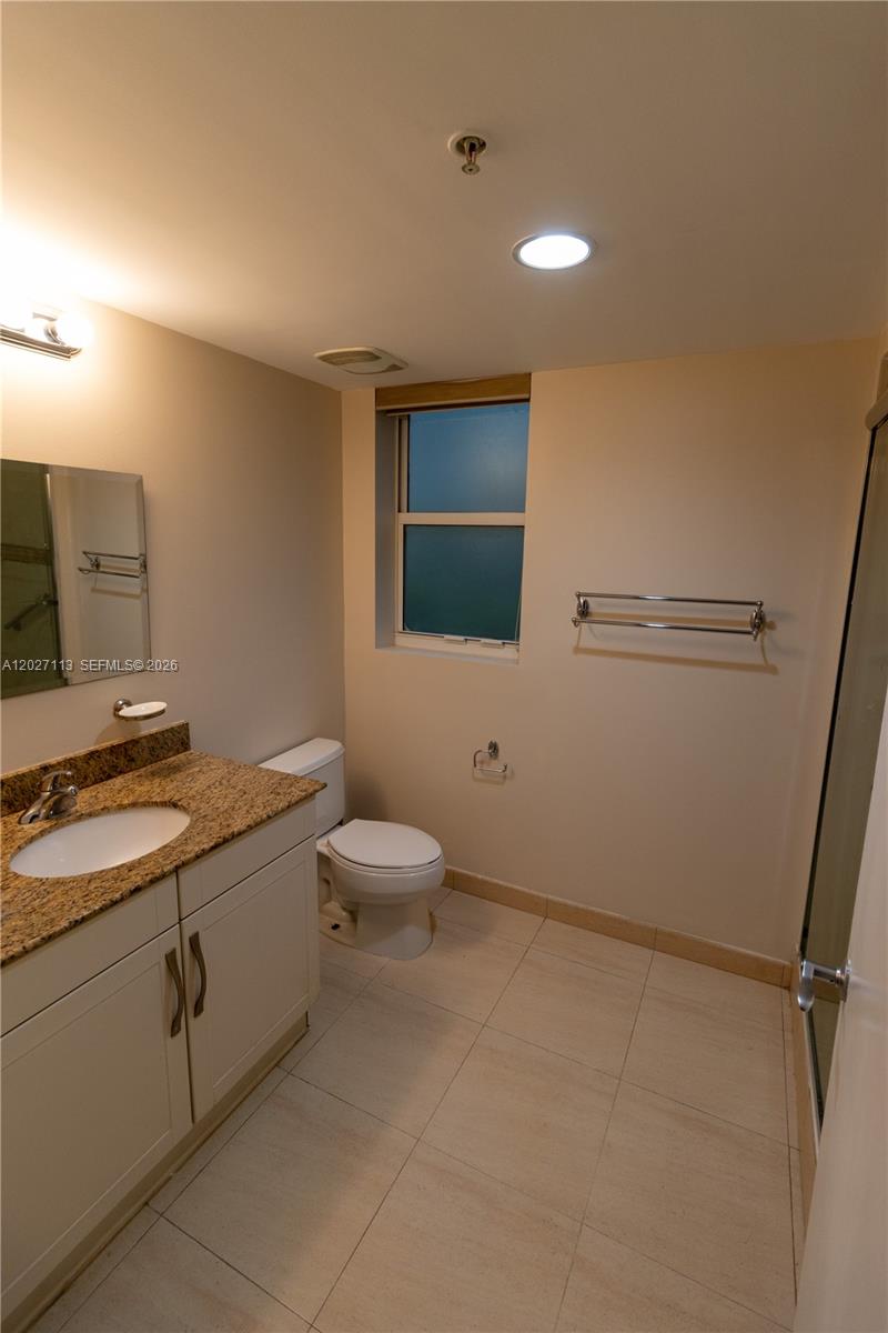 7275 Southwest 90th Way, Unit 213 Miami, FL 33156 - Photo 24 of 31 a bathroom with a granite countertop sink a toilet and mirror