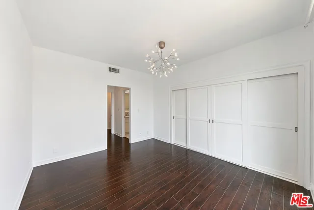 a spacious bedroom with a large bed couch and a potted plant
