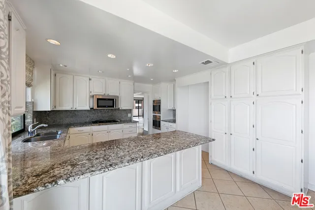 a large kitchen with stainless steel appliances kitchen island granite countertop a sink and cabinets