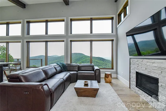a living room with furniture a floor to ceiling windows and a fireplace