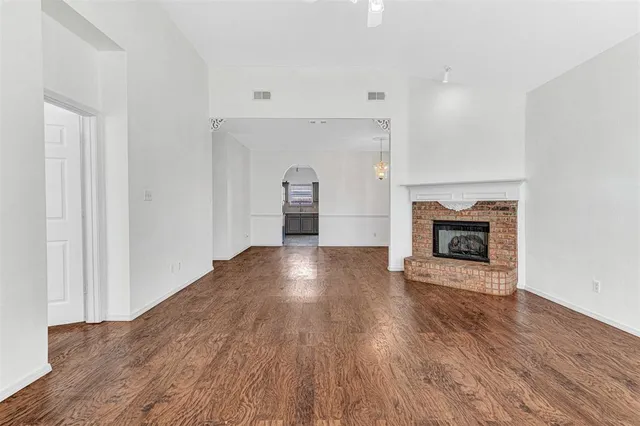 a view of empty room with wooden floor and fireplace