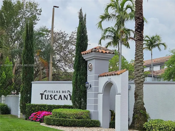 a view of sign board with flower plants and wooden fence