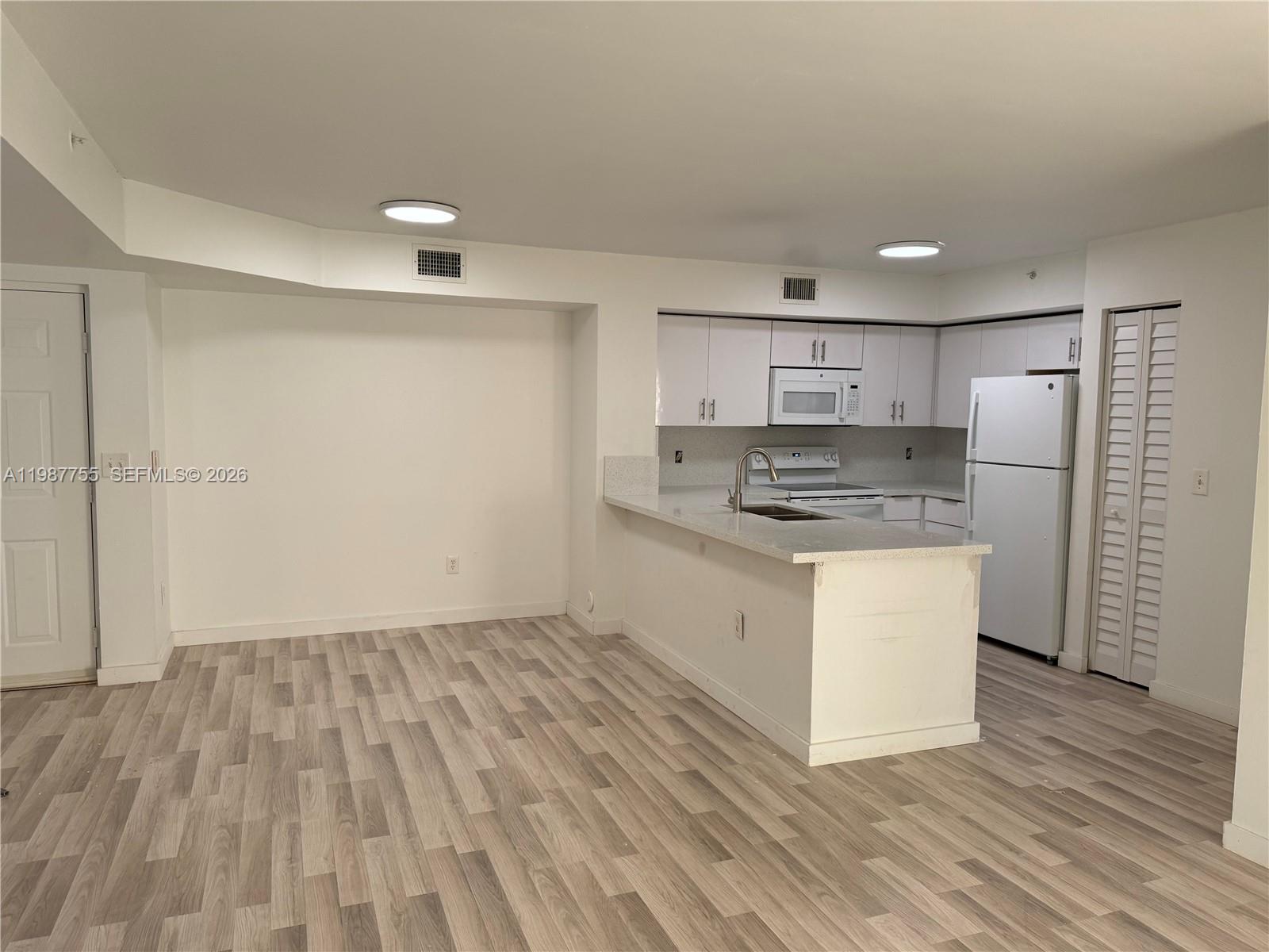 2071 Renaissance Boulevard, Unit 104 Miramar, FL 33025 - Photo 8 of 17 a kitchen with granite countertop white cabinets and white appliances