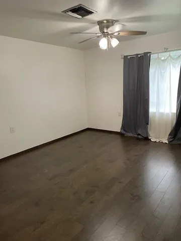 an empty room with windows and fan