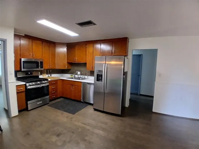 a kitchen with granite countertop a refrigerator and a stove top oven