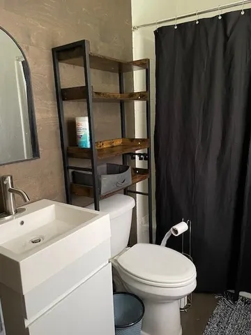 a bathroom with a sink a toilet a mirror and shower