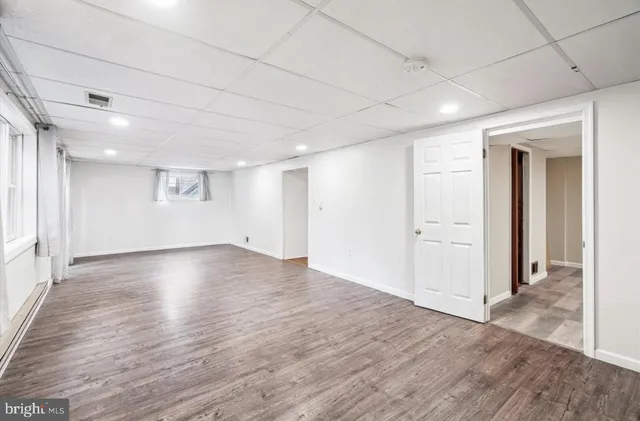 an empty room with wooden floor & windows and bathroom