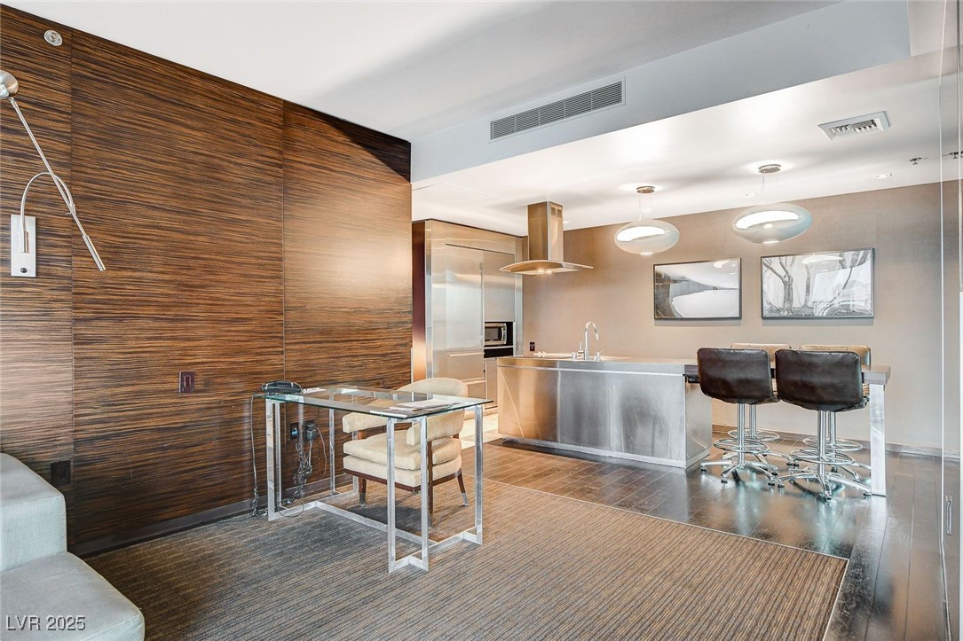 4381 West Flamingo Road, Unit 2202 Las Vegas, NV 89103 - Photo 12 of 40 Kitchen with island range hood, wood finished floors, stainless steel microwave, light countertops, and pendant lighting