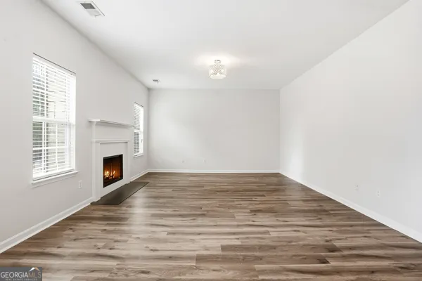 a view of empty room with fireplace and wooden floor