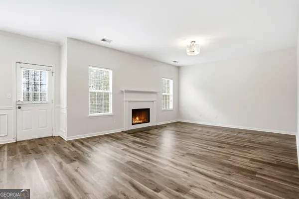 an empty room with wooden floor fireplace and windows