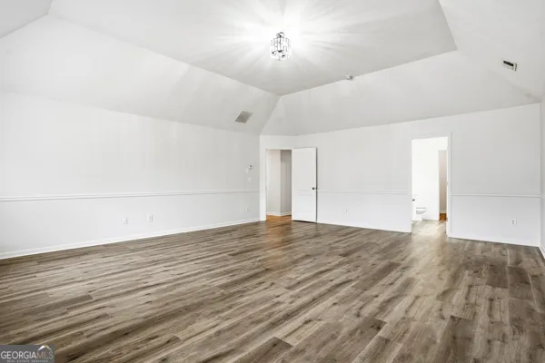 a view of an empty room with wooden floor and a ceiling fan