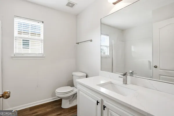 a bathroom with a granite countertop toilet a sink a mirror and a window