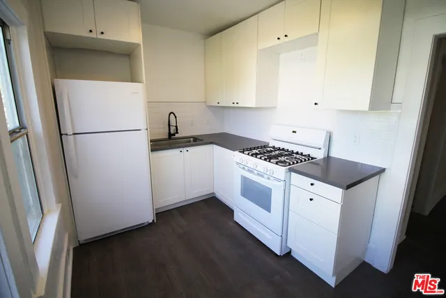 a kitchen with granite countertop white cabinets and white appliances
