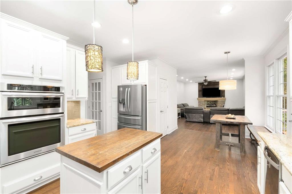 4200 Cherry Grove Road Ball Ground, GA 30107 - Photo 17 of 64 a kitchen with stainless steel appliances a stove a sink dishwasher a refrigerator white cabinets and wooden floor next to a window
