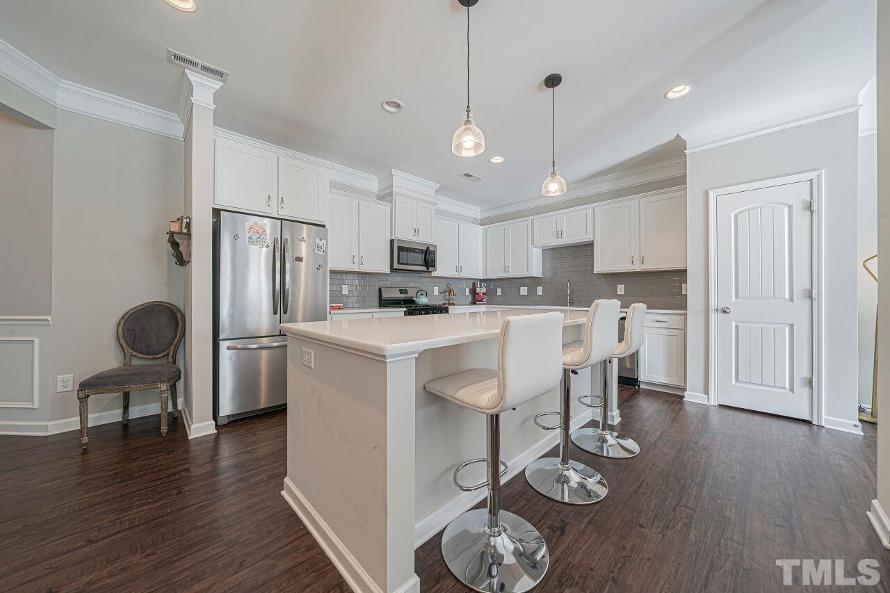 6343 Grace Lily Drive Raleigh, NC 27607 - Photo 5 of 24 a kitchen with stainless steel appliances kitchen island granite countertop a dining table chairs refrigerator sink and cabinets