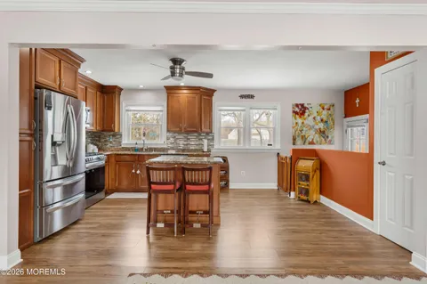 a kitchen with stainless steel appliances granite countertop a refrigerator a stove top oven a sink dishwasher and white cabinets with wooden floor