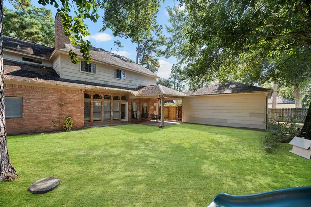 a backyard of a house with plants and large tree