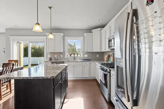 a kitchen with stainless steel appliances granite countertop a sink a stove and a refrigerator