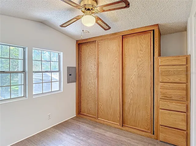 an empty room with wooden floor closet and windows