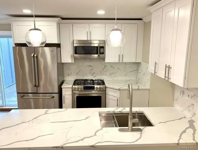 a kitchen with stainless steel appliances kitchen island granite countertop a refrigerator a stove a sink and a microwave