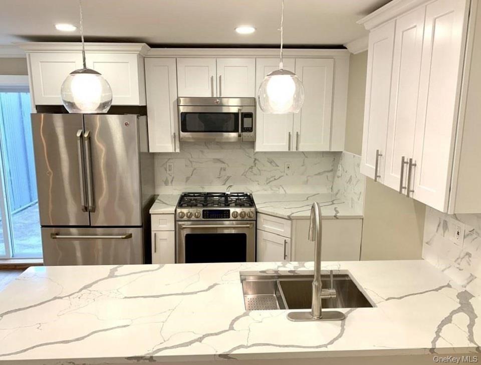 2301 Bathgate Avenue Bronx, NY 10458 - Photo 8 of 25 a kitchen with stainless steel appliances kitchen island granite countertop a refrigerator a stove a sink and a microwave