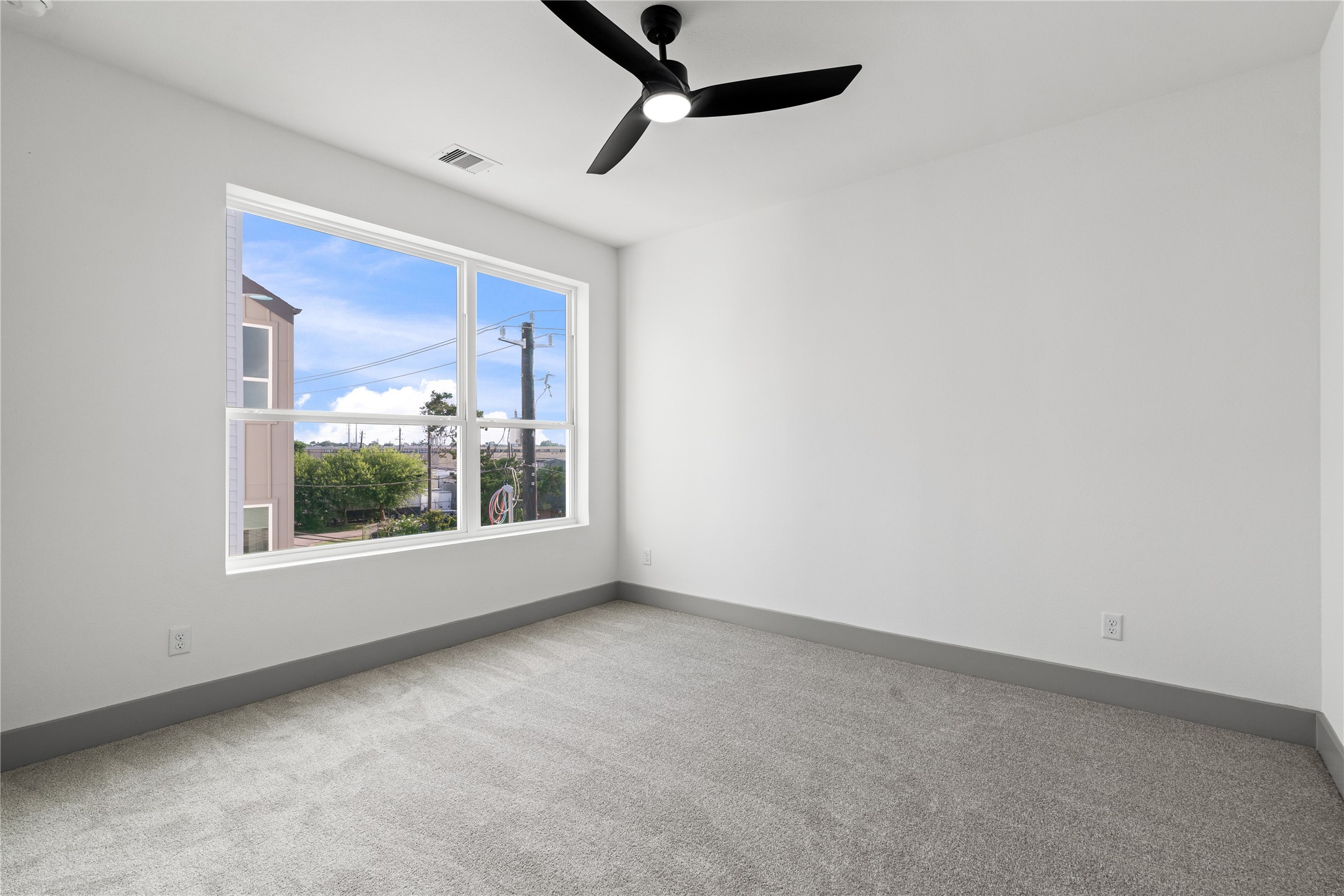 2950 Pitzlin Street Houston, TX 77023 - Photo 29 of 37 Bright and spacious, this secondary bedroom offers plush carpet, modern trim, and an oversized window that frames neighborhood views and floods the room with natural light—perfect as a guest suite, nursery, or creative flex space.