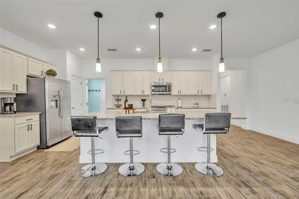 134 Silver Maple Road Groveland, FL 34736 - Photo 16 of 73 a kitchen with stainless steel appliances kitchen island granite countertop a dining table chairs sink and microwave