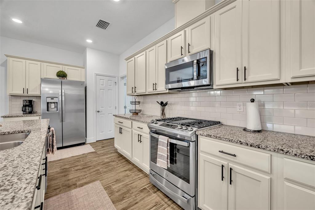 134 Silver Maple Road Groveland, FL 34736 - Photo 22 of 73 a kitchen with stainless steel appliances granite countertop a stove a refrigerator and a white cabinets