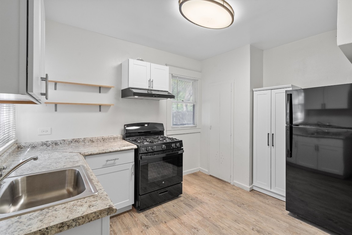 3404 Grooms Street, Unit B Austin, TX 78705 - Photo 4 of 11 Kitchen featuring black appliances, a sink, under cabinet range hood, light countertops, and light wood-type flooring