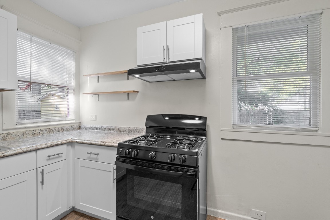 3404 Grooms Street, Unit B Austin, TX 78705 - Photo 6 of 11 Kitchen featuring black range with gas cooktop, under cabinet range hood, white cabinetry, and healthy amount of natural light