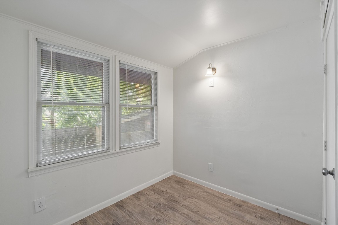 3404 Grooms Street, Unit B Austin, TX 78705 - Photo 8 of 11 Spare room featuring vaulted ceiling, wood finished floors, baseboards, and ornamental molding