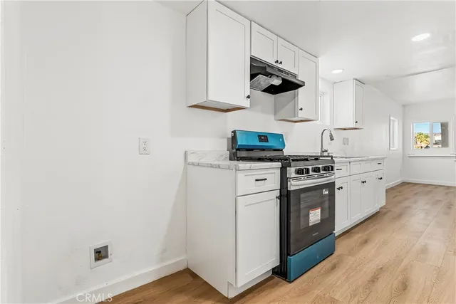 a kitchen with stainless steel appliances a sink a stove a refrigerator and white cabinets