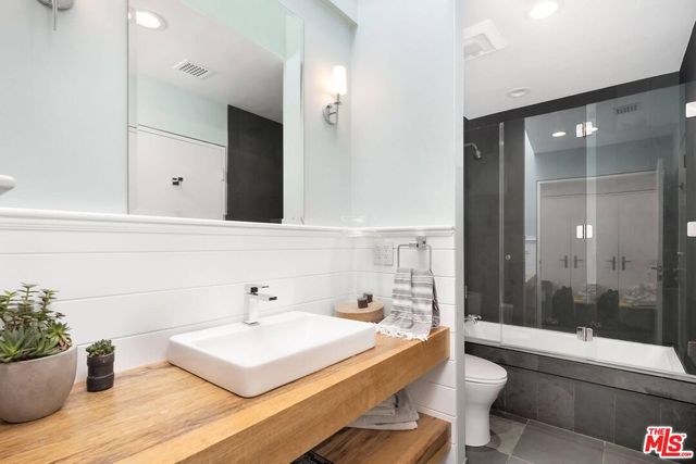 a bathroom with a sink a toilet a mirror and bathtub