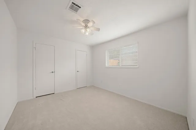 en empty room with windows and chandelier fan