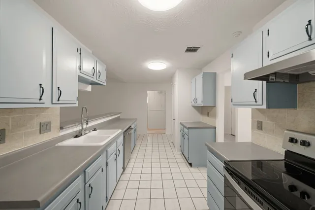 a kitchen with a sink stainless steel appliances and white cabinets