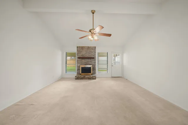 an empty room with a fireplace and a ceiling fan
