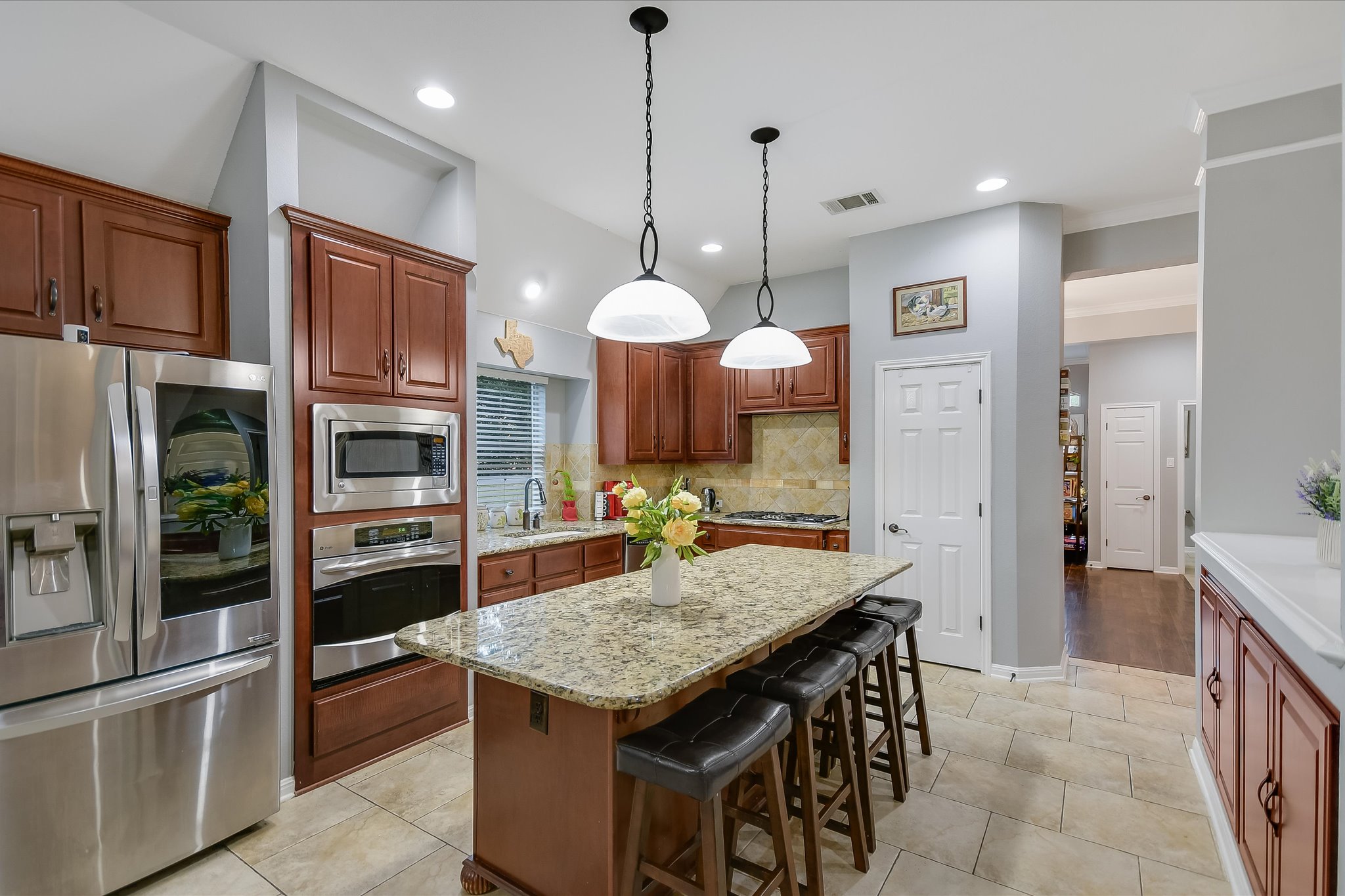 300 Wesley Ridge Drive Spicewood, TX 78669 - Photo 12 of 40 The gourmet kitchen features rich cabinetry, granite countertops, and stainless steel appliances, anchored by a spacious center island with seating for casual dining.