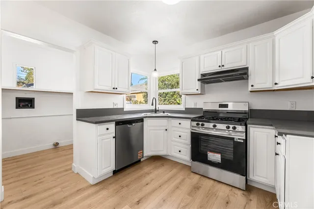 a kitchen with stainless steel appliances white cabinets granite counter tops and a hard wood floors