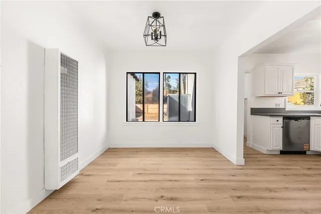 a view of an empty room with window and wooden floor