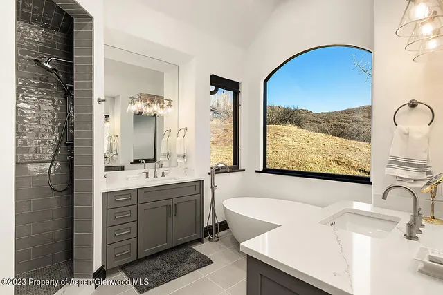 a bathroom with a double vanity sink mirror and bathtub