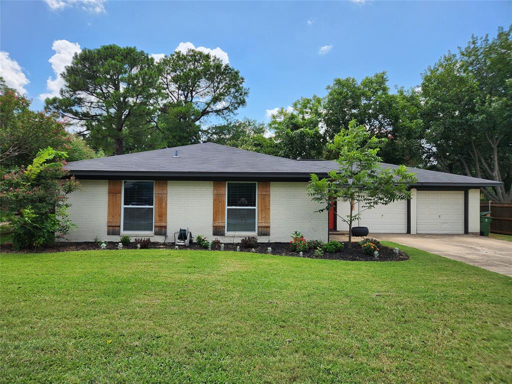 Ranch-style house featuring concrete driveway, a garage, brick siding, and a front lawn