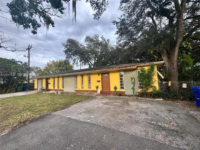 front view of house with a yard and trees